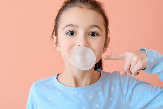 Cute Little Girl With Chewing Gum On Color Background