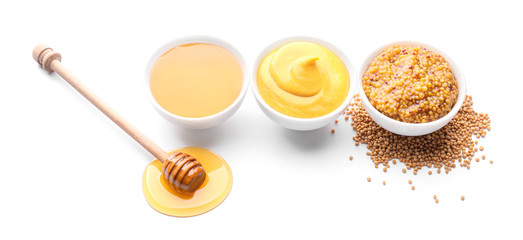 Bowls of honey, mustard and sauce on white background