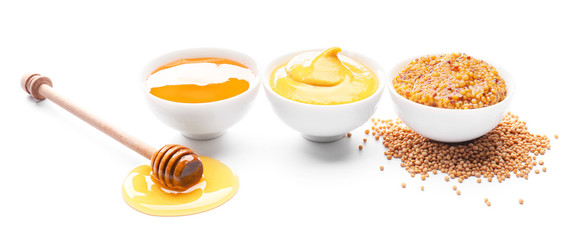 Bowls of honey, mustard and sauce on white background