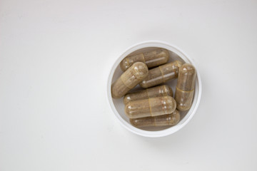 Herbal capsule and powder on white background.