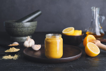 Jar of tasty honey mustard sauce on dark background