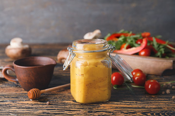 Jar of tasty honey mustard sauce on wooden table