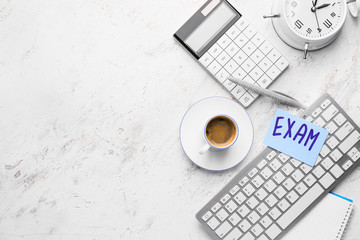 Cup of coffee with computer keyboard, alarm clock, calculator and paper sheet with text EXAMS on white background