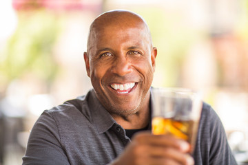 Mature African American man drinking at a restaurant.