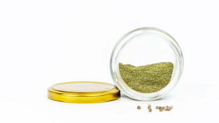 Close-up of glass jar with hashish and cannabis seeds isolated on white background.