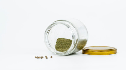 Close-up of glass jar with hashish and cannabis seeds isolated on white background.