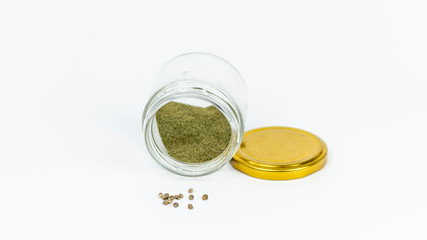 Close-up of glass jar with hashish and cannabis seeds isolated on white background.