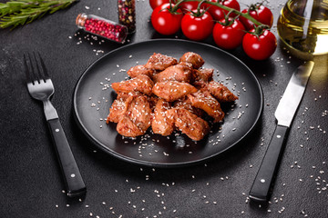 Chicken fillet in sesame seeds, teriyaki sauce on a black stone plate