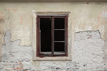Fototapeta na wymiar Old wooden window, no glass, just frame on an old abandoned building with weathered facade 
