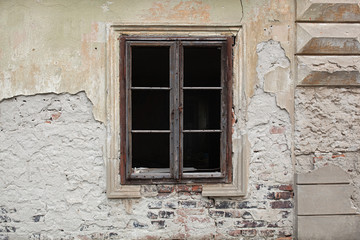 Old wooden window, no glass, just frame on an old abandoned building with weathered facade 