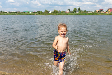Fototapeta na wymiar Joyful child frolics in the water. drops splashing water