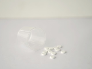 white color tablets pills capsule heap mix therapy drugs with clear plastic glass on white paper