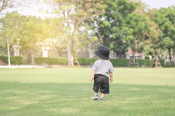 boy looking at tree and light when his walking on the green grass 