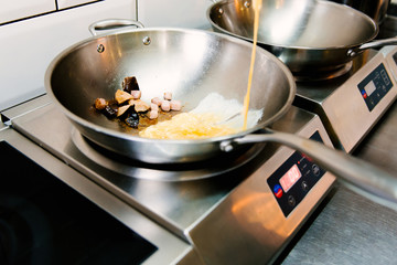 Cooking scrambled eggs in a metal pan in a cafe, selective focus