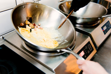 Cooking scrambled eggs in a metal pan in a cafe, selective focus