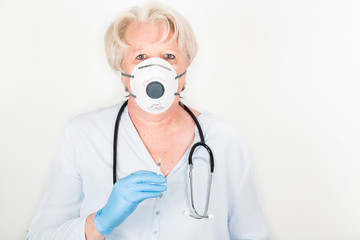 Close-up of a mature caucasian doctor with blond hair wearing a face mask to protect herself from coronavirus infection or air pollution. With stethoscope