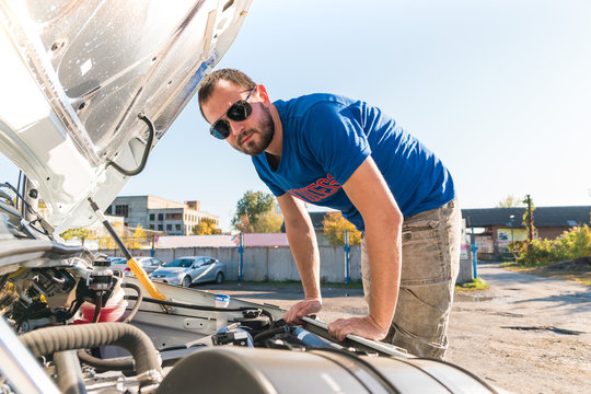 A Man Driver Is Repairing A Truck With An Open Hood.