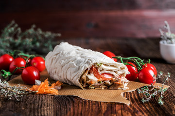 Fresh Dürüm (Yufka) kebab in flatbread with salad and vegetables served on a rustic wooden plate