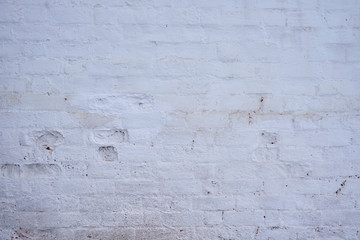 Background. An old, dirty, white brick wall with peeled paint and peeled plaster.