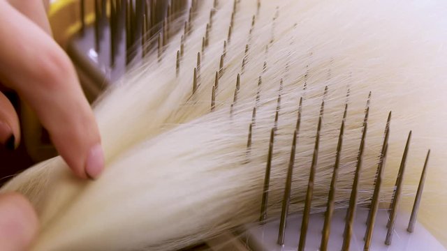Wig production, female hands close-up. Wig Hair Combing
