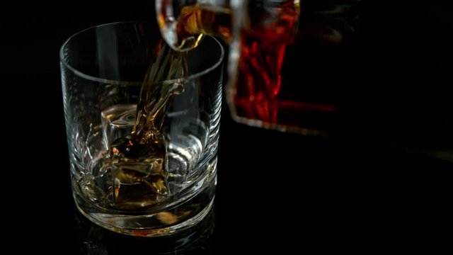 Super Slow Motion Shot of Pouring Whiskey into Glass with Ice Cubes at 1000fps with Camera Movement.