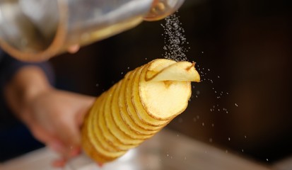 tornado potatoe on a stick being salted