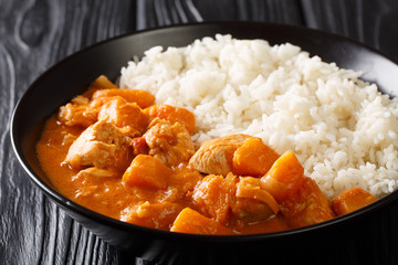 Domoda, a delicious peanut stew, is the national dish of Gambia. The rich and delicious vegetable and meat stew is served over rice close-up in a plate. Horizontal
