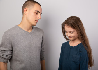 Young serious teen father have a dialog with his small school girl daughter. Happy joyful emotions on toned vintage color background.