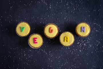 Pretty yellow vegan Easter cupcakes with colorful pastel icing vegan wording