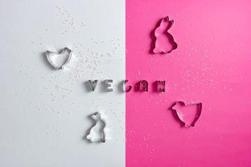 Shapes and stencils of Easter bunny rabbit and chick on pink and white background with vegan...