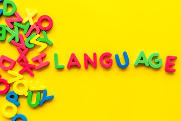 Learn foreign language. Concept with letters on yellow background top-down copy space