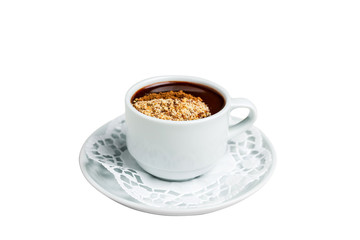 A small white cup of dark hot chocolate with nutmeg and cinnamon on a white saucer and a napkin