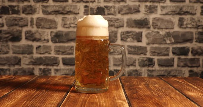Filling a glass of beer wrong with foam overflow and slowly floating down