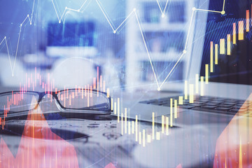 Financial chart hologram with glasses on the table background. Concept of business. Double exposure.