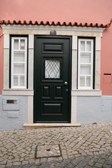 Adorable door and window on building with pink facade in Lagos, Portugal, on a very sloped cobblestone road