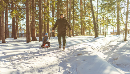 man and child on the sledge in winter forest
