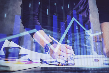 Double exposure of man writing on paper with forex graph.