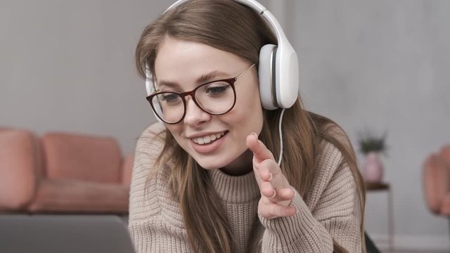 Young woman having video chat. Happy woman using laptop for chatting on internet with friends, family in the living room. Pretty girl talking at laptop computer on Skype or social media