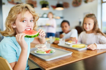 Junge in der Kantine isst eine Melone