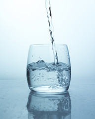 Water jet falling into glass with splashes and drops, air bubbles from a stream of water in glass....