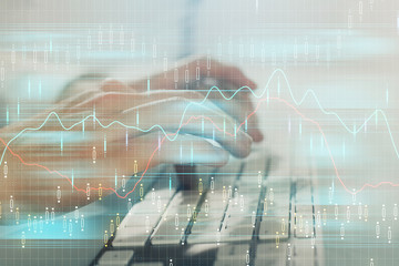 Double exposure of graph with man typing on computer in office on background. Concept of hard work. Closeup.
