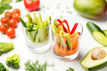salad of fresh vegetables light salad in a glass on a white table with a composition of tomatoes, avocado, parsley, cucumbers, peas, broccoli