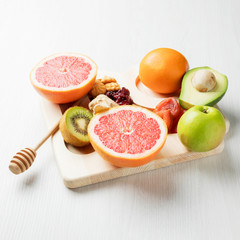 sliced fruit, dried fruit, nuts on a wooden Board and a white table