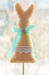 Easter felt rabbit in beige color, decorated with lace and a bow on a skewer. Handmade. Decoration for the Easter holiday