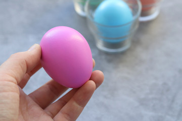 Pink decorated Easter egg in a woman's hand on a gray background. Selective focus. The symbol of Easter.
