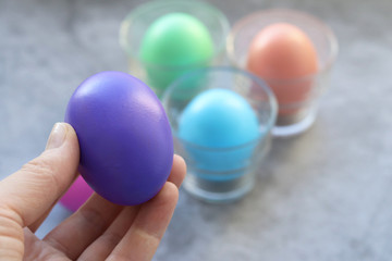 Purple Easter egg in a woman's hand on the background of other eggs. Selective focus. The symbol of Easter.