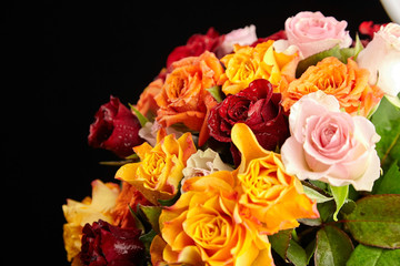 Bouquet of different color roses with water drops on petals on a black background. Red, orange and pink flowers. Romantic Valentine's Day Gift