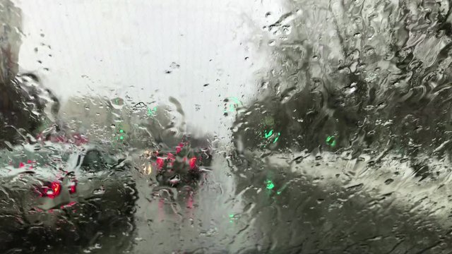 Snow is melting on the windshield of a car. Windshield wipers do not work when approaching a traffic light.