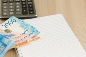 Money.Russian rubles, a calculator and a notebook for writing on the table.The concept of...