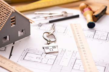 A model house on blueprints with keys to the new home.